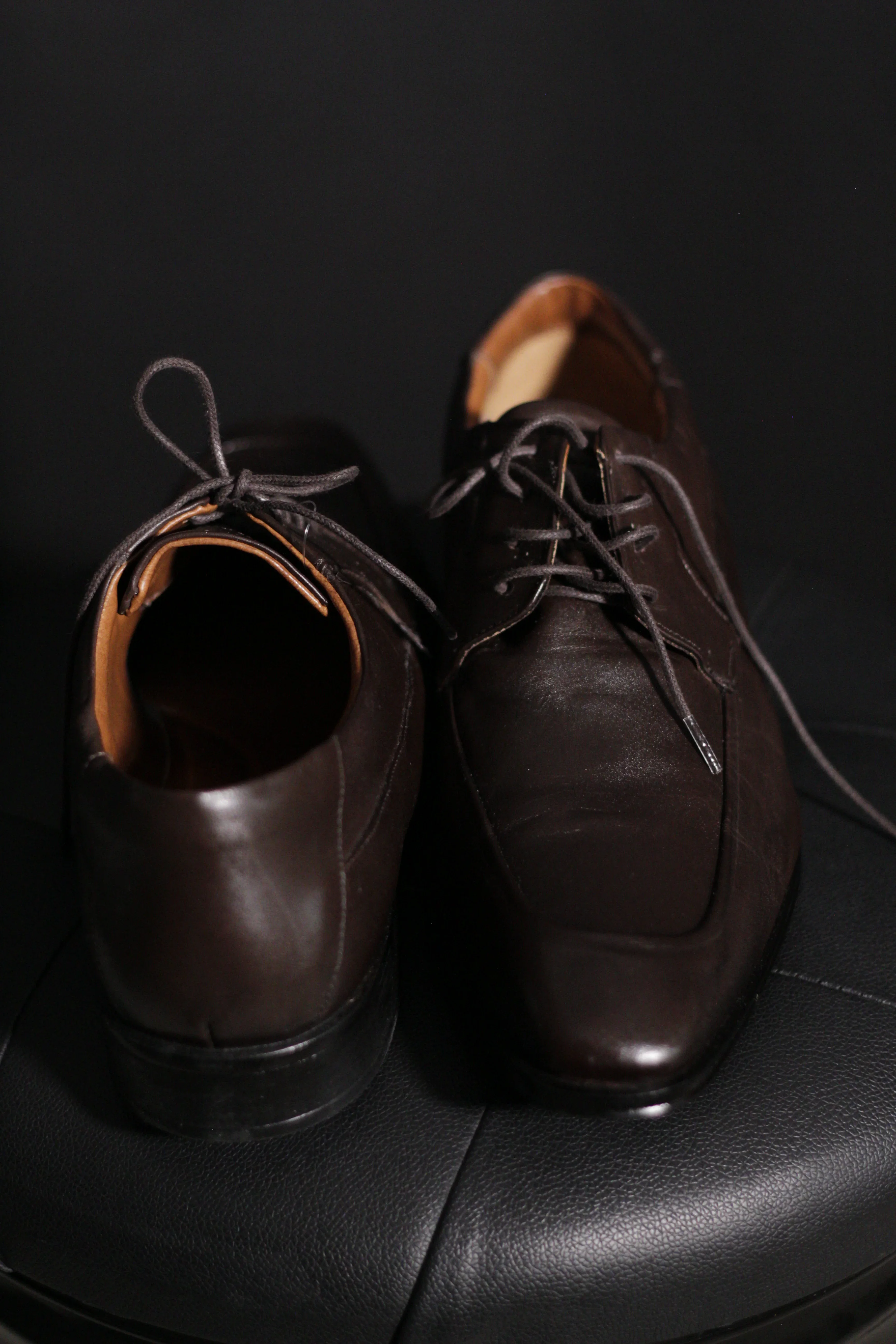 Detalhe de sapatos sociais em couro marrom.